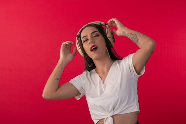 istock young woman with headphone acting as a DJ and a studio photo red background. 1397102021
