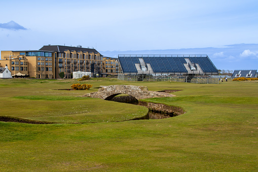 St. Andrews, Scotland, United Kingdom - April 28, 2022: View of Swilken Bridge on the 18th fairway of the Royal and Ancient Gold Club of St Andrews (old course). St Andrews is the oldest golf course in existence.