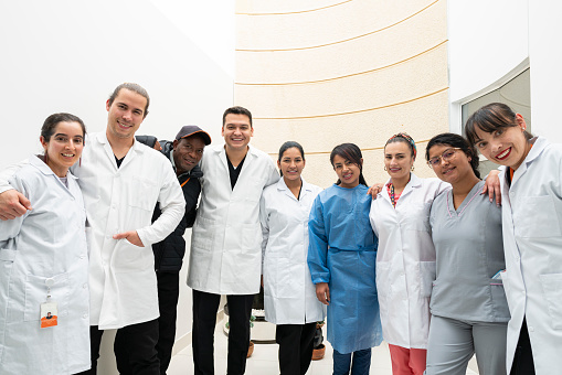 group of Latino male and female doctors in their mid-30s and early 40s dressed in their scrubs and scrubs are photographed side by side looking at the camera