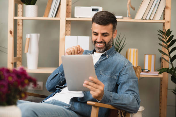 istock Mid adult man relaxing and using tablet at home 1397116035