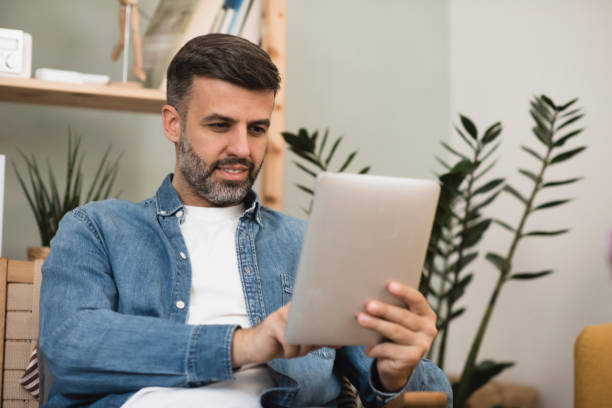 istock Mid adult man relaxing and using tablet at home 1397116036