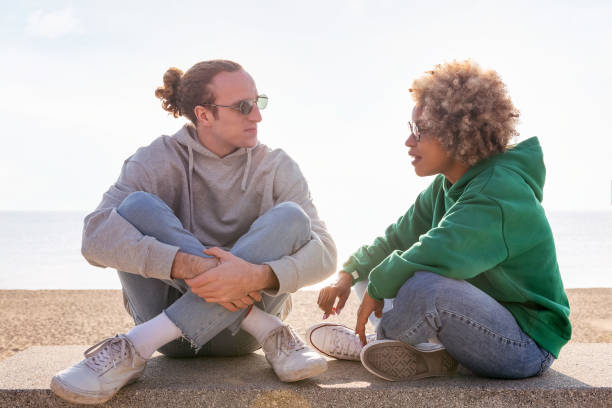 joven pareja charlando al atardecer sentada en un banco - couple black american culture african culture fotografías e imágenes de stock