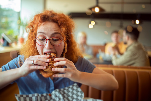 The student takes a break from studying by eating her favorite hamburger.