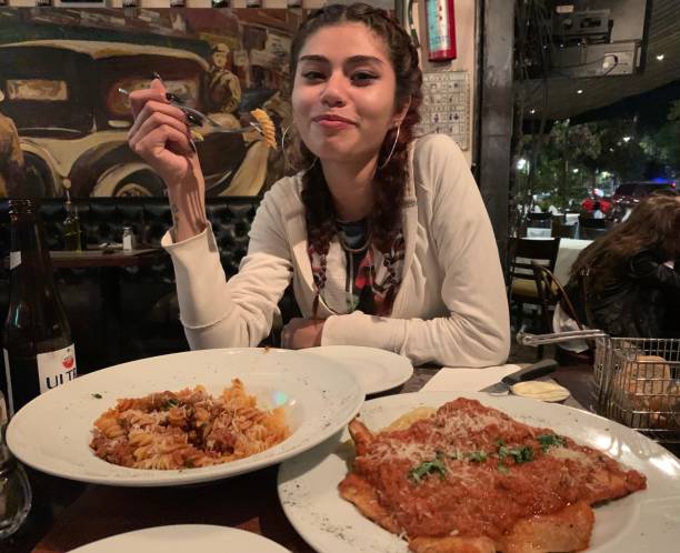 Couple having a romantic dinner, eating a plate of spaghetti with tomato sauce and basil, seen from above