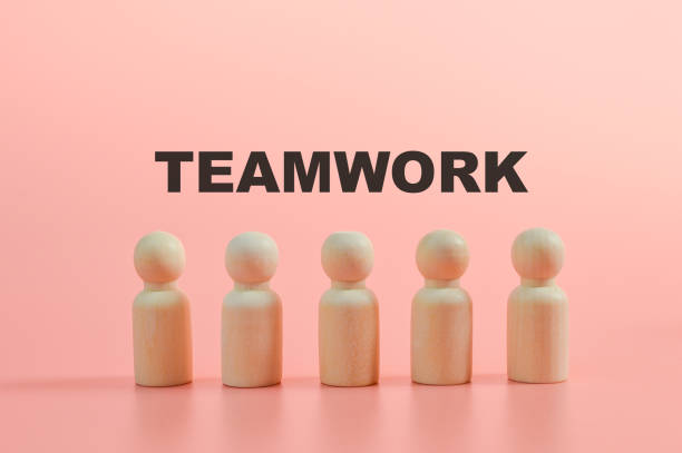 istock Wooden figures of people standing in a row with text TEAMWORK 1397133464