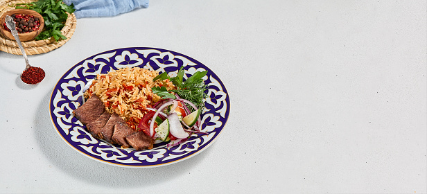 Traditional uzbek food - plov with beef. Eastern cuisine - pilaf with rice, meat and spices. Plov with beef on traditional uzbek plate. Composition of oriental ceramic plate with pilaf