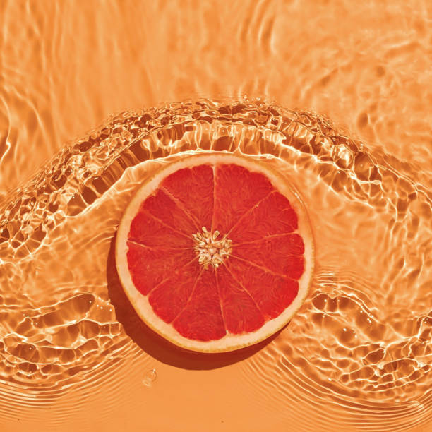 cítricos de pomelo en agua dulce con olas sobre fondo brillante. - splashing orange fruit water fotografías e imágenes de stock