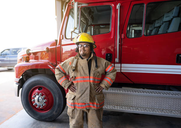 istock Confident Firefighter wearing protection suit standing in front of a fire engine truck 1397140932