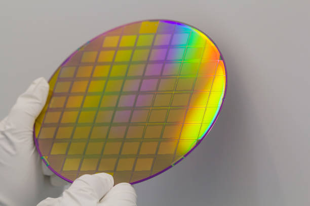 istock Hands in white gloves holding a silicon wafer on a white background. 1397148375