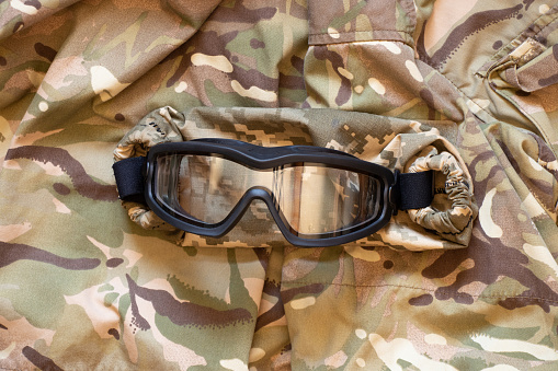 Military tactical glasses for a soldier lie on a camouflage background, military uniform