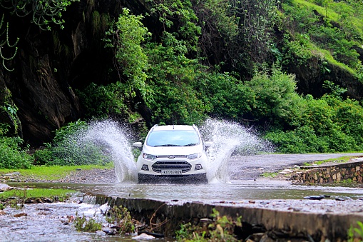 Udaipur, India - August 08 2017: Water splashed while crossing small river by Ford Ecosport