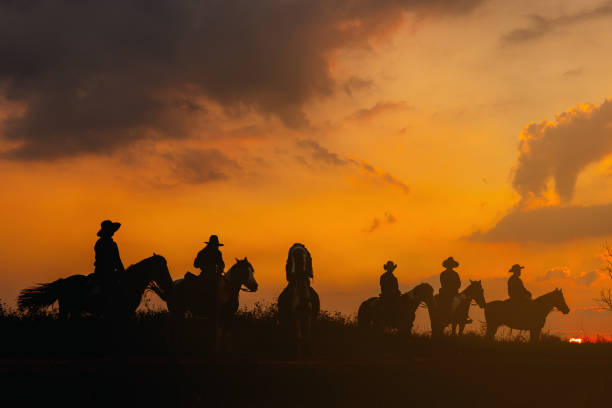 group cowboy on horse silhouetted against a large sky