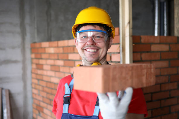 Happy builder holds brick for masonry and smiles stock photo