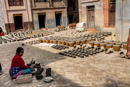 Madhyapur Thimi, Nepal - oct 28, 2019: a woman checks and refines clay vases and bowl placed to dry in a square of Thimi before final baking, Kathmandu Valley