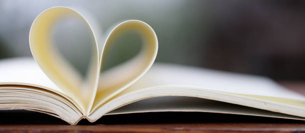форма сердца крупным планом из бумажной книги на деревянном столе с винтажным размытым фоном - abstract newspaper macro heart shape стоковые фото и изображения