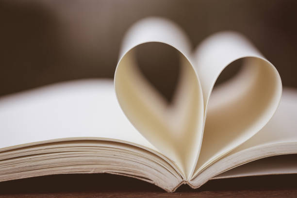 форма сердца крупным планом из бумажной книги на деревянном столе с винтажным размытым фоном - abstract newspaper macro heart shape стоковые фото и изображен�ия