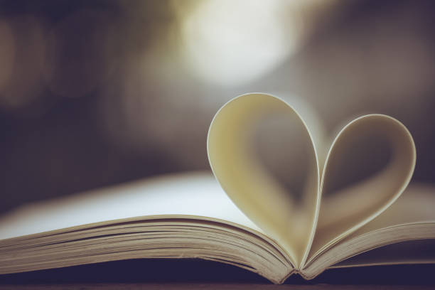 Close up heart shape from paper book on wooden table with vintage blur background Close up heart shape from paper book on wooden table with vintage blur background abstract newspaper macro heart shape stock pictures, royalty-free photos & images