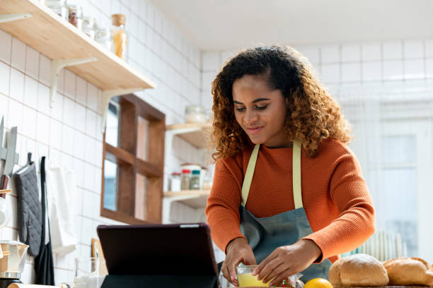 istock Focused African American woman preparing food at table in kitchen while recording process on tablet for vlog 1397156357