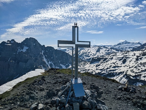 summit cross on the fronalstock in the canton of glarus. Spring hike above netstal. View of the murtschenstock