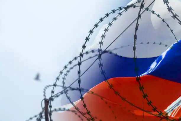 Photo of Flag of Russia on the background of barbed wire. Martial law in Ukraine. Stop war