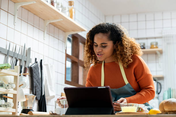 istock African American female vlogger in apron standing at table and looking down while creating online lesson on food preparation 1397164262
