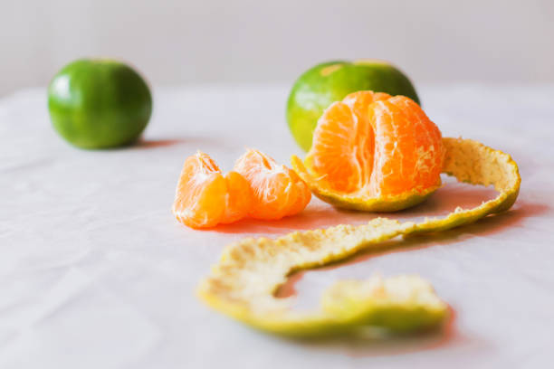 Close-up ,The oranges  on the  table on white backdrop .The oranges have green peel . The fruit have many vitamin C,peeling orange