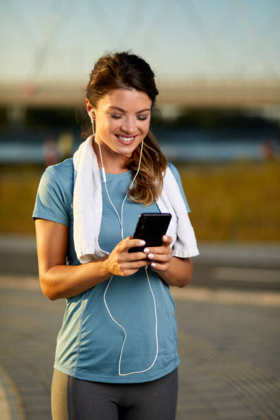 istock Female runner adjusting music on mobile phone before jogging 1397165091