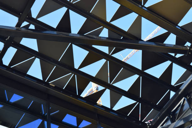 istock Graphic pattern of black triangles and lines against clear blue sky with yellow building crane in the background 1397165483