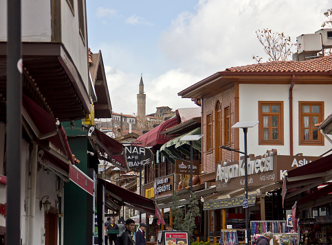 Ankara, Turkey - April 12, 2022: People at an old street near the Historical Ankara restoration houses around the pavement alley in Hamamönü district of Altindag, Ankara, Turkey. There is lots of wooden ottoman houses, cafes, vendors at old bazaar.