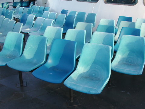 rows of empty blue seats on the deck of a ship