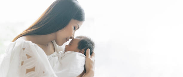 image de bannière panoramique d’une belle jeune mère asiatique embrassant et étreignant le nouveau-né. belle famille. concept de maternité. parentalité. maternité, concept d’adoption - baby kissing mother lifestyles photos et images de collection