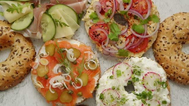 Bagel sandwiches with various toppings, salmon, cottage cheese, hummus, ham, radish and fresh herbs