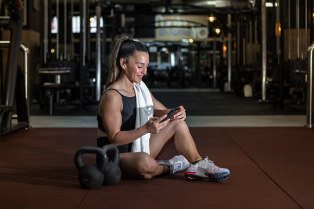 istock Smiling sportswoman using smartphone while resting after training in gym 1397177255