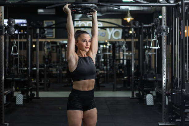 istock Strong confident sportswoman doing overhead press with weight plate 1397177259