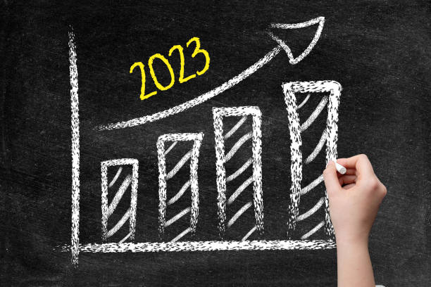 istock 2023 ascending arrow and bar graph on blackboard with woman hand 1397180864