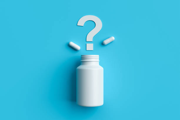 istock Plastic medical container and white capsule pills with question mark on blue background top view. 1397181784