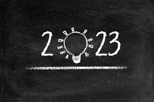 2023 Ideas text in lightbulb for creative idea concept, computer graphic with chalk drawings black board