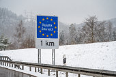 Snow is falling around a sign for European border, frontier between Germany and Austria