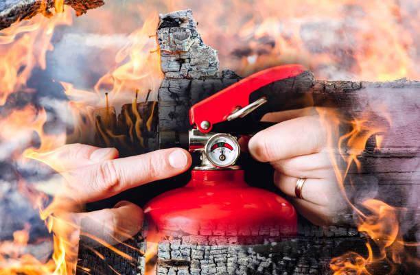 istock Close up view of man worker showing red fire extinguisher and controlling it. Maintenance service concept. Photo composite. 1397184615