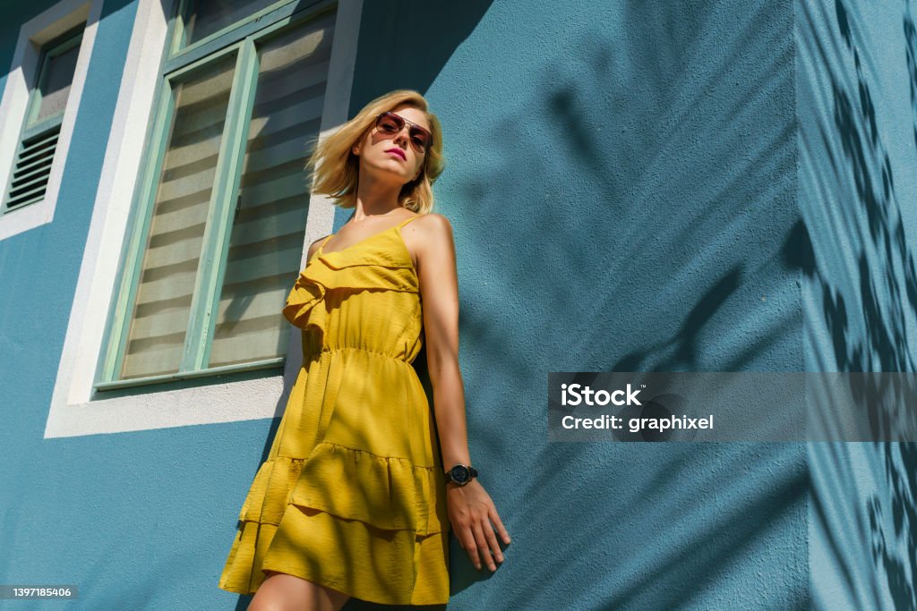 Portrait of woman smiling against wall with palm tree shade Fashion Stock Photo