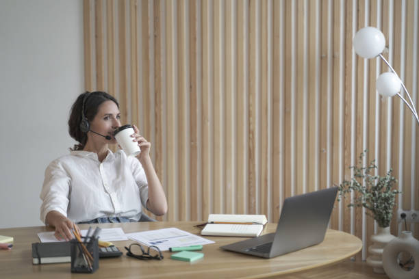 istock Satisfied positive Spanish female entrepreneur in wireless headset drinking coffee in office 1397185666