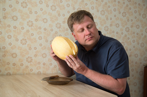 adult man is blond with large yellow fragrant melon waiting for lunch.