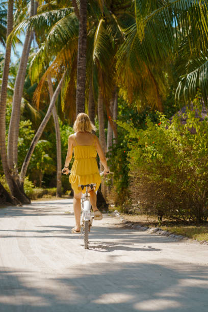istock Beautiful woman riding bicycle under palm trees 1397185795