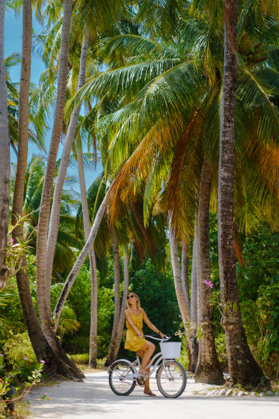 istock Beautiful woman riding bicycle under palm trees 1397186391