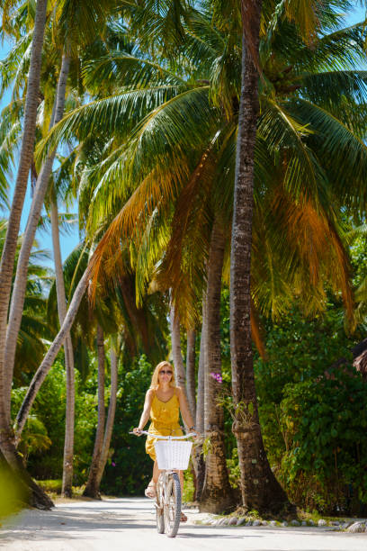 istock Beautiful woman riding bicycle under palm trees 1397186454