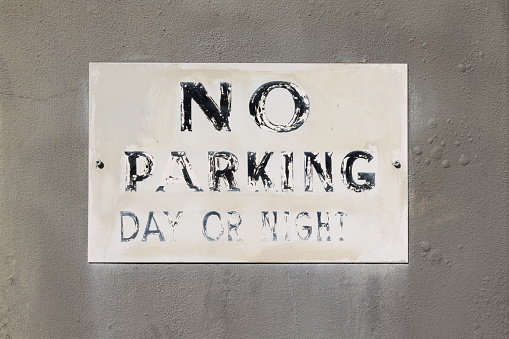 No Parking written long ago on an old white sign.