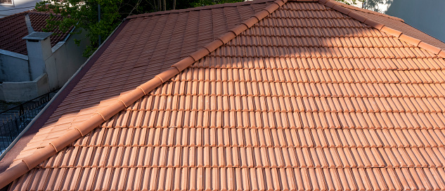 a roofer nails on the roof tiles