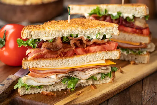 Club sandwich made with bacon, ham, turkey, cheese, lettuce and tomato on toasted bread