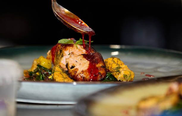 istock Fish dish: fried or baked salmon with vegetables and sauce on a black background 1397196556