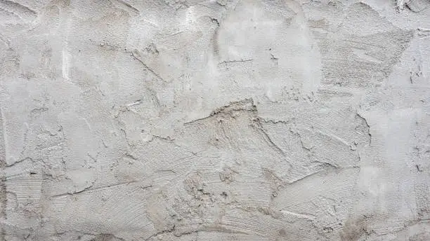 Photo of The textured background of the cement wall, plastered with a rustic simplicity with scratch marks.